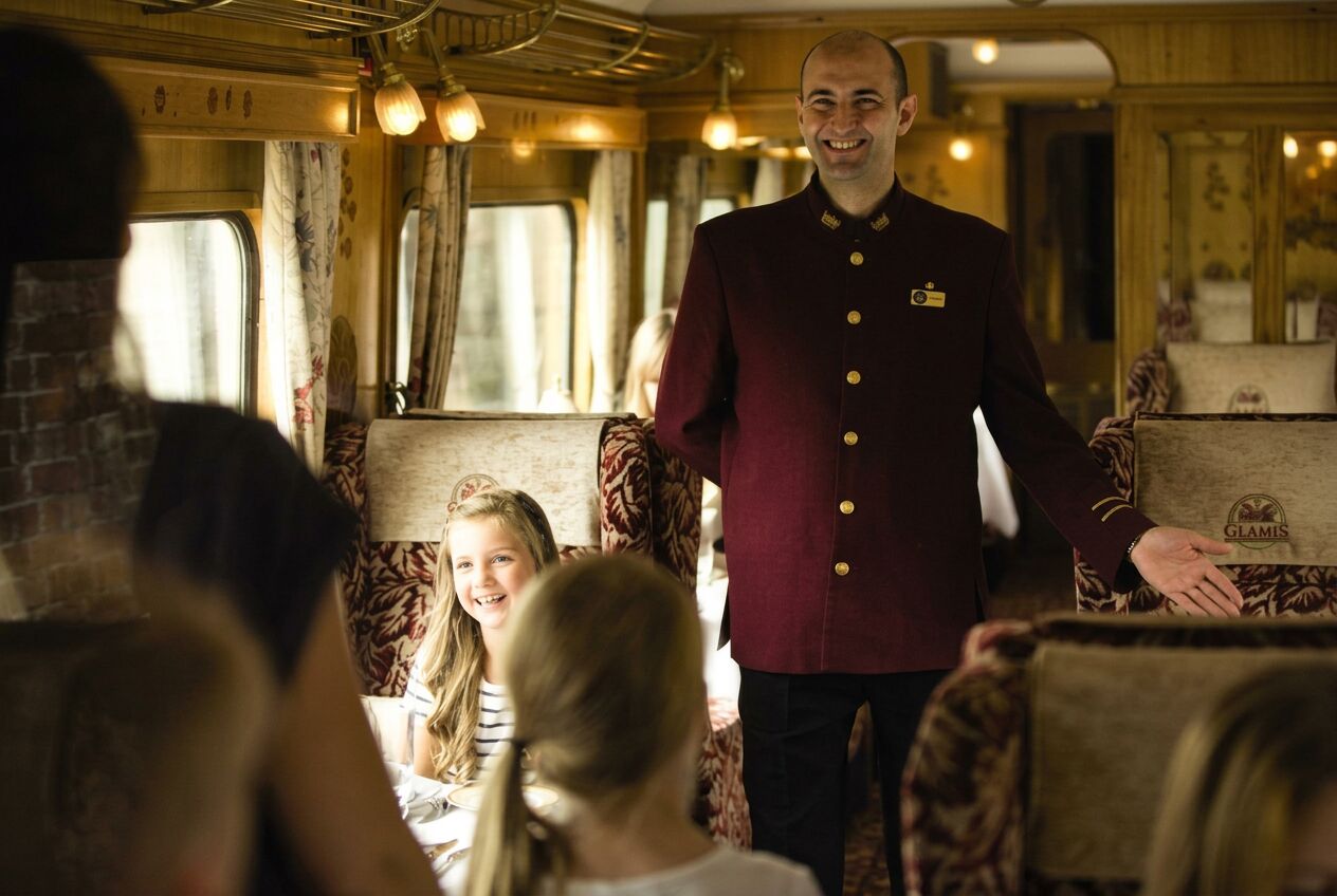 Family raising glasses in the dining carriage of a luxury heritage train
