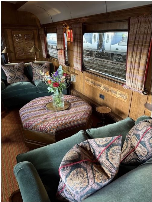 Lounge area inside a luxury train carriage with green sofas